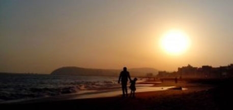 father and child on beach at sunset