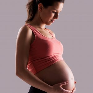 Beautiful pregnant woman isolated over grey background